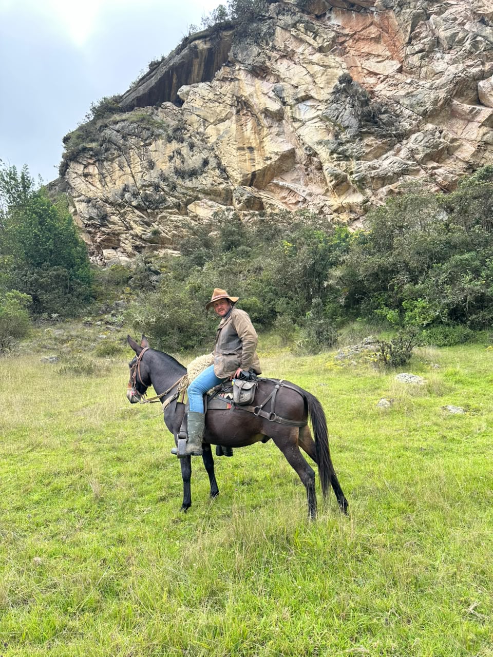 Jinete en mula sobre un potrero bajo una pared de roca en la cabalgata Suesca – Nemocón, Suesca