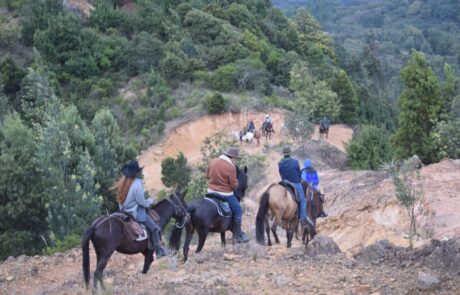 Jinetes bajando por tierra rojiza entre montañas verdes en la cabalgata Suesca – Cucunubá, Suesca